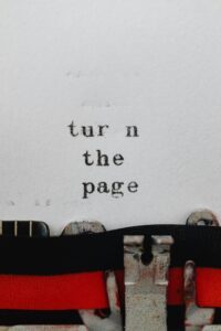 Close-up of a vintage typewriter with the phrase 'turn the page' on paper.